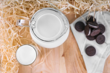 top view of milk in a glass and jug on a wooden background with cookies. Natural farm concept