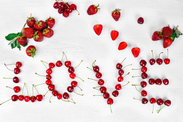 inscription love made of sweet cherry and strawberry on a white background. Beautiful background