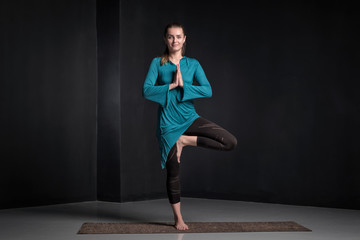 European young woman working out standing in Vriksasana Posture, Tree Pose