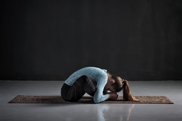Young woman working out doing yoga or pilates butterfly exercise, sitting in baddha konasana