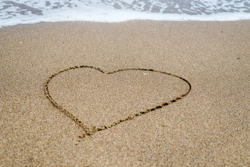 Fototapeta na wymiar Heart drawn in the sand on the beach, ocean.