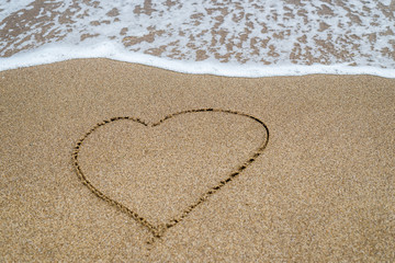 Heart drawn in the sand on the beach, ocean.
