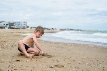 A little boy is played on the sand by the sea, ocean.