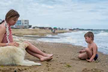 Mum with the small son and a dog have a rest on the seashore, ocean.