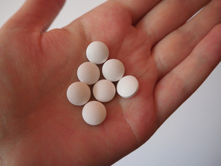 White medicine pills in person's hand. Healthcare and medical concept. Suicide by overdosing on medication concept. Opioid epidemic, painkillers and drug abuse concept.
