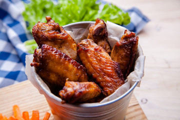 Baked chicken wings with sesame seeds and sweet chili sauce on white wooden board.