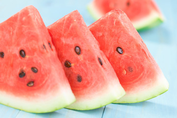 Fresh juicy watermelon slices photographed on blue wood (Selective Focus, Focus on the front of the...