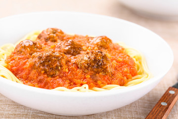 Spaghetti with homemade meatballs and fresh tomato sauce in bowl (Selective Focus, Focus on the front of the meatball on the right)