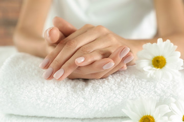 Obraz na płótnie Canvas Woman with smooth hands and flowers on towel, closeup. Spa treatment