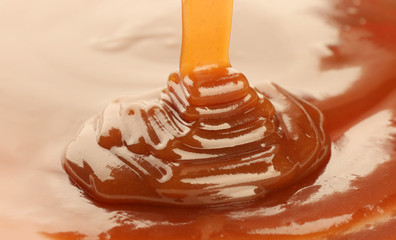 Pouring delicious caramel sauce as background, closeup - obrazy, fototapety, plakaty