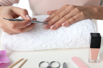 Obraz na płótnie Canvas Woman preparing fingernail cuticles at table, closeup. At-home manicure