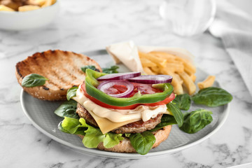Plate with tasty burger on marble table