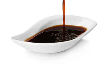 Pouring tasty soy sauce into bowl isolated on white