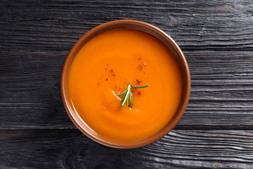 Bowl of tasty sweet potato soup on wooden table, top view
