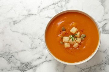 Bowl of tasty sweet potato soup on marble table, top view. Space for text