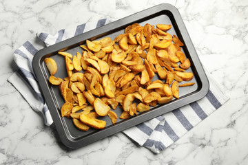 Sheet pan with delicious oven baked potatoes on marble background, flat lay