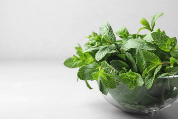 Glass bowl with fresh green mint on table. Space for text