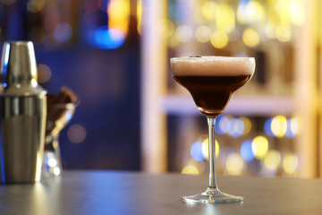 Glass of Espresso Martini on counter in bar, space for text. Alcohol cocktail
