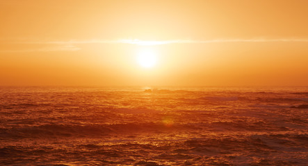 Beautiful soft golden light over the ocean at sunset with sun in center above horizon