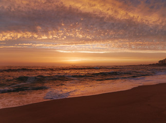 Wide angle view over beach at sunset in Portugal with beautiful clouds