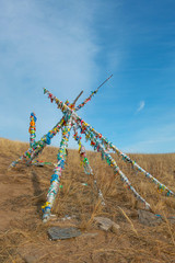 shaman wood that lean against in triangle tied with many of colorful ribbons; religion belief.