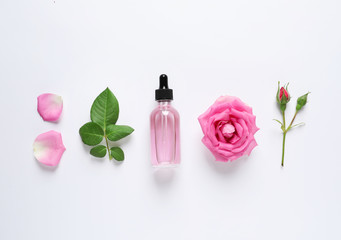 Composition with rose essential oil and flowers on white background, top view