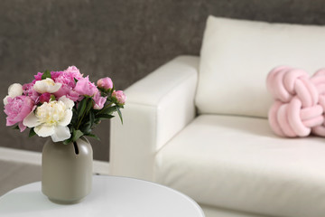 Vase with bouquet of beautiful peonies on table in room, space for text