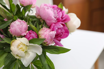 Bouquet of beautiful peonies on table in room, closeup. Space for text