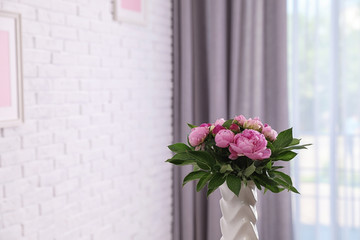 Fototapeta premium Vase with bouquet of beautiful peonies at white wall in room, space for text