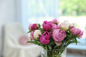 Vase with bouquet of beautiful peonies in room, space for text