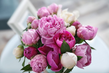 Bouquet of beautiful peonies on table in room, closeup