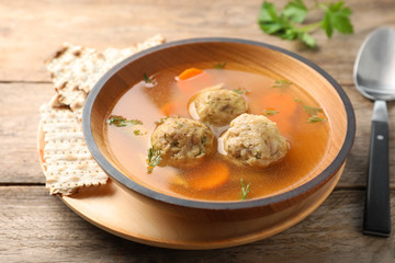 Bowl of Jewish matzoh balls soup on wooden table