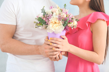 Obraz na płótnie Canvas Young couple with bouquet of beautiful flowers on light background, closeup