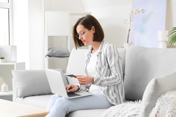 Young woman with credit card and laptop shopping online at home