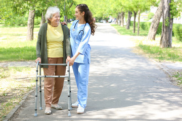Caregiver walking with senior woman in park