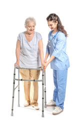Young caregiver with senior woman on white background