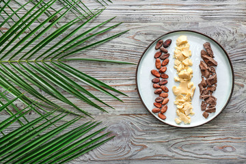 Plate with cacao butter, chocolate and beans on wooden table