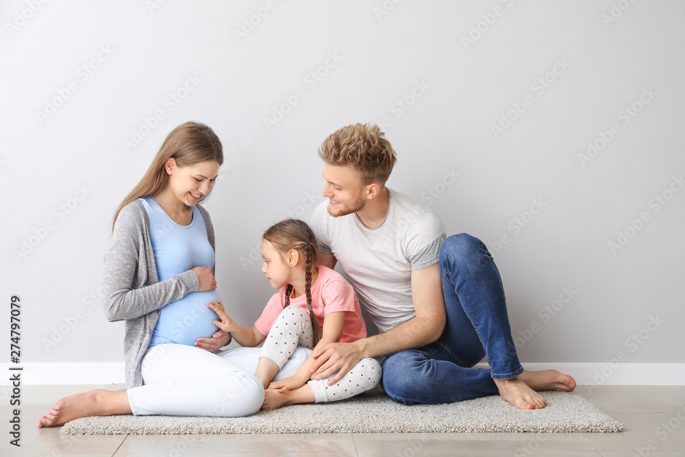 Canvas Prints Beautiful pregnant woman with her family sitting near light wall