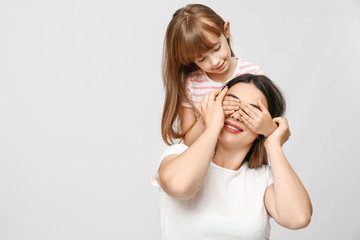 Portrait of happy mother and daughter on light background