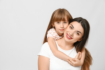 Portrait of happy mother and daughter on light background