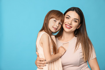 Portrait of happy mother and daughter on color background
