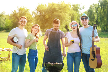 Friends cooking tasty food on barbecue grill outdoors