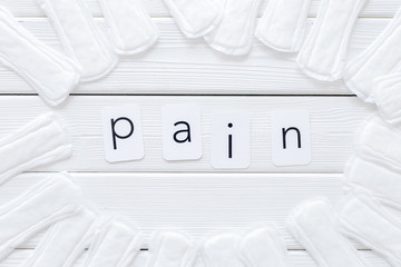 Menstruation calendar concept with sanitary pads and pain copy on white wooden background top view