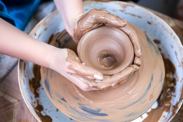 Fototapeta premium Hands of Experienced Female Potter Working with Clay. Posing with Clay Lump on Potter's Wheel in Workshop.