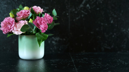 Black marble counter benchtop with vase of pink Eustoma lisianthus flowers with copy space.