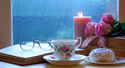 Nostalgia scene relaxing by the window on a cold rainy day with old books and cup of tea and copy space.