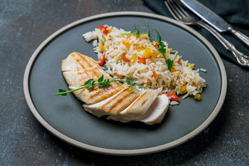 sliced Grilled chicken Breasts with rice and vegetables on grey plate
