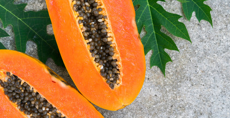 Fresh orange papaya with papaya green leaves on a  stone background. Tropical Fruit. Top view. Free text space.