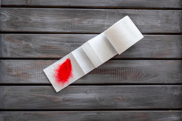Toilet paper roll and feather for proctology diseases concept on wooden background top view