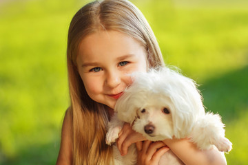 Little girl with a maltese puppy, outdoor summer